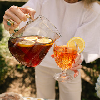 close up image of woman pouring tea into a clear glass with ice in it