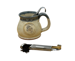 stainless steel tea infuser pipe with tea in it and mug in the background
