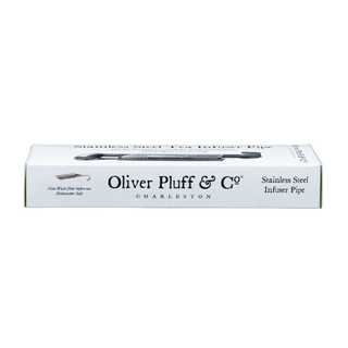 A boxed stainless steel tea infuser pipe by Oliver Pluff & Co., shown in its white retail packaging with a bright yellow-green side panel, photographed on a solid green background.