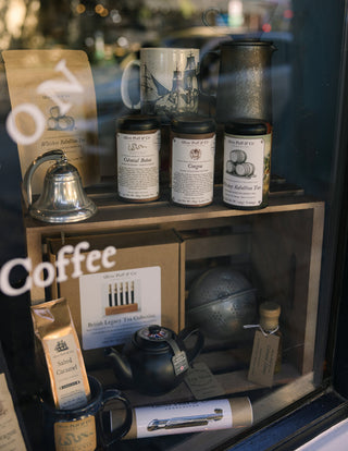 Display of coffee products including mugs, tins, and a teapot in a store window.