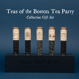 5 tubes of green or black tea with labels in black rectangular stand on blue background