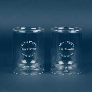 Two clear glass tumblers with 'Oliver Pluff's Tea Traveler' text on a dark blue background