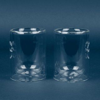 Two clear glass tumblers on a dark blue background