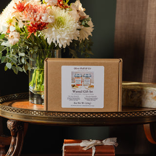 wassail gift set in kraft box on wooden table with floral arrangement and marble box in the background