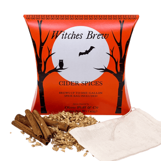 A package of Witches Brew Cider Spices Wassail with cinnamon sticks, ground ginger, and nutmeg displayed in front of a cauldron-shaped graphic on the package.