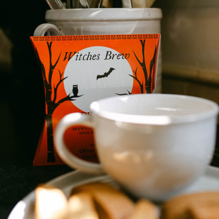 witches brew packaging on countertop behind white cup