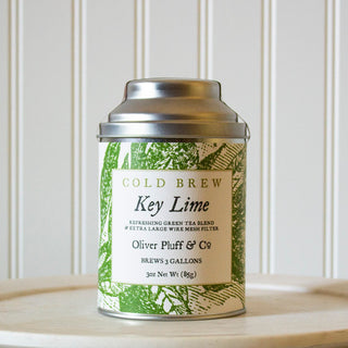 small silver tea tin with green flowery design on label sitting on white plate in kitchen