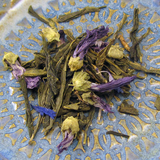 zoom in view of purple flowers and yellow tea leaves on blue and yellow plate