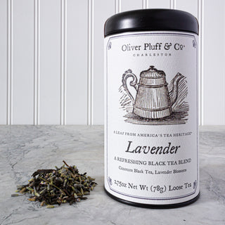 black tea tin with old timey graphic of a teapot, beside pile of loose leaf tea on white kitchen counter