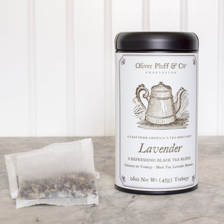 black tea tin with old timey graphic of a teapot, beside pile of white mesh tagbags on white counter