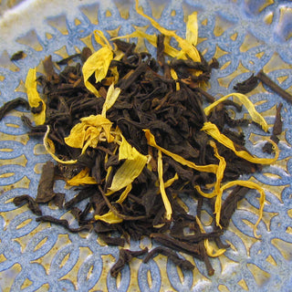 pile of yellow and dark green loose leaf tea on blue and yellow plate