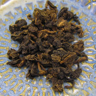 close up view of golden yellow oolong tea leaves on blue and yellow plate