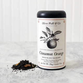 black tea tin with black and white graphic of an orange on a leaf. Loose leaf tea sprinkled beside it. On white kitchen counter