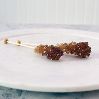 two Amber Rock Sugar Swizzle Sticks on white plate