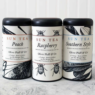 three black tea tins in a row on white kitchen counter